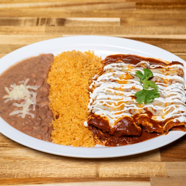 A plate of enchiladas with red sauce, sour cream, rice, and refried beans with cheese.